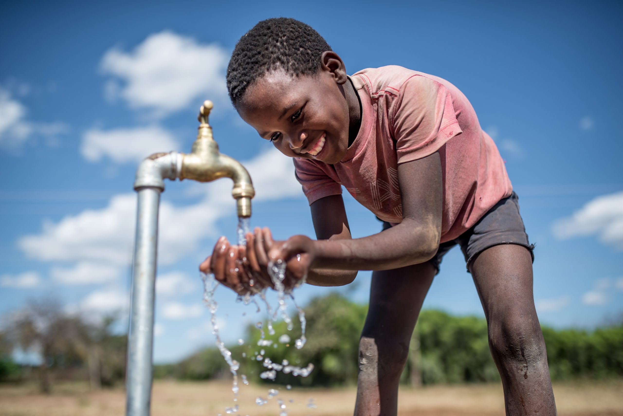 Purity, 10, at a tap connected to an Oxfam solar piped water system in Zimbabwe Credit: Aurelie Marrier D’Unienville / Oxfam